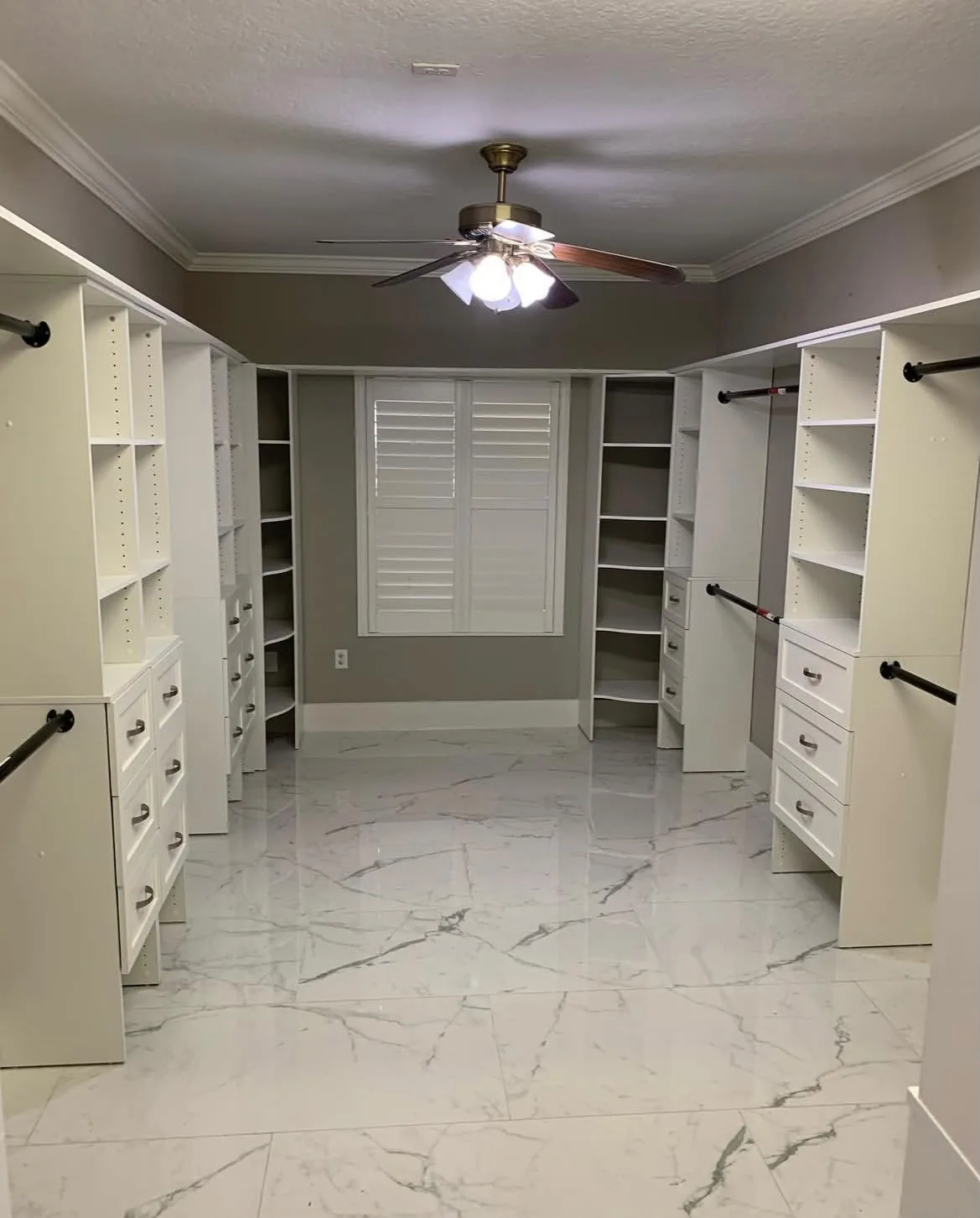Wide view of finished walk-in closet with white marble-look large-format tile flooring