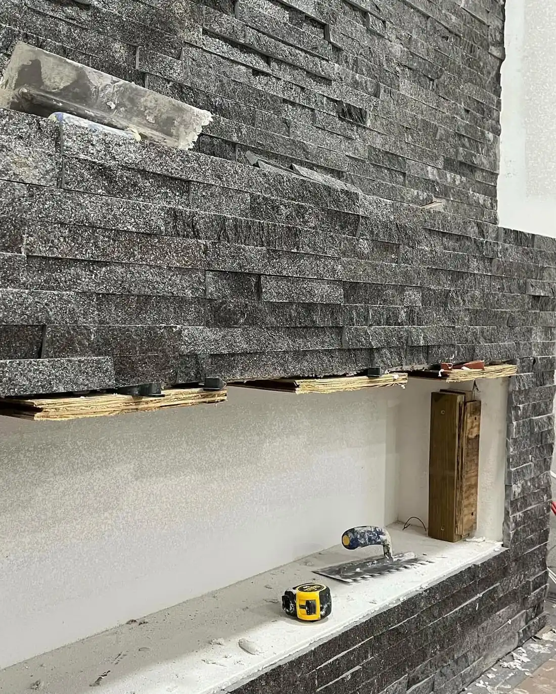 Split-face stone veneer being installed edge to edge on a feature wall
