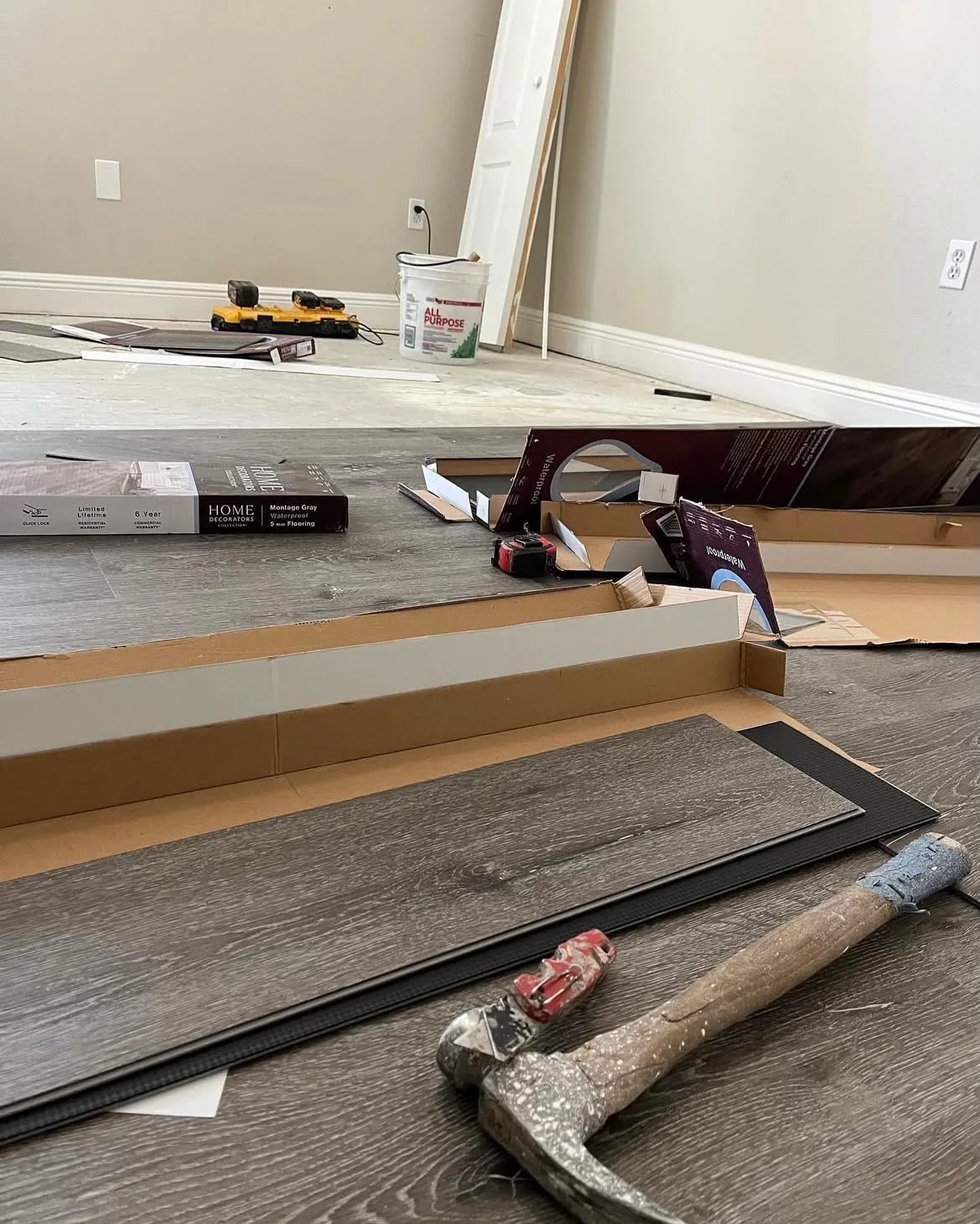 Waterproof gray vinyl plank boxes and click-lock planks staged for installation