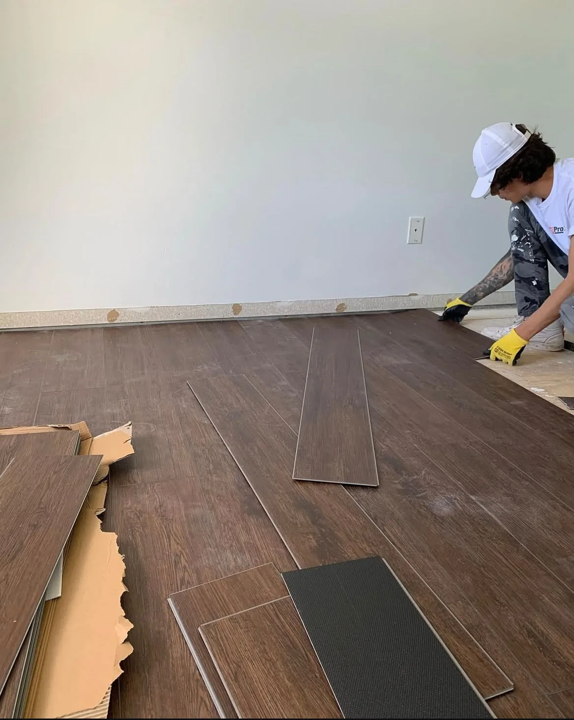 Installer setting walnut vinyl plank flooring boards along the wall