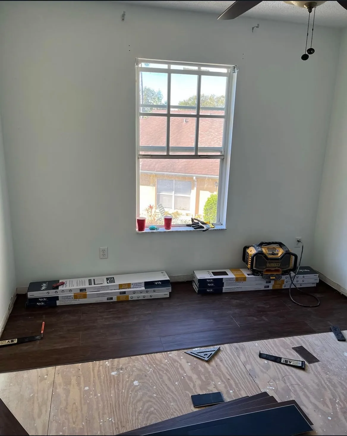 Walnut vinyl plank flooring installation over plywood subfloor with boxes staged